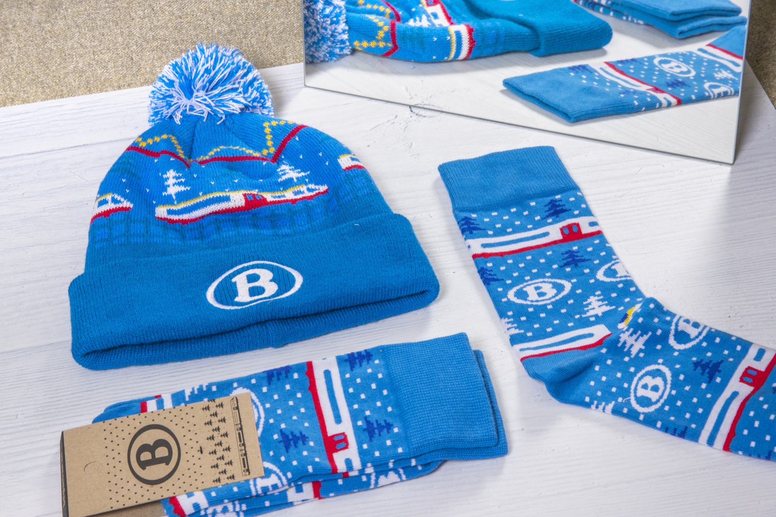 Branded company swag detail: an NMBS bobble hat with the B logo on the front, next to NMBS socks, illustrating visible versus non-visible logo placement