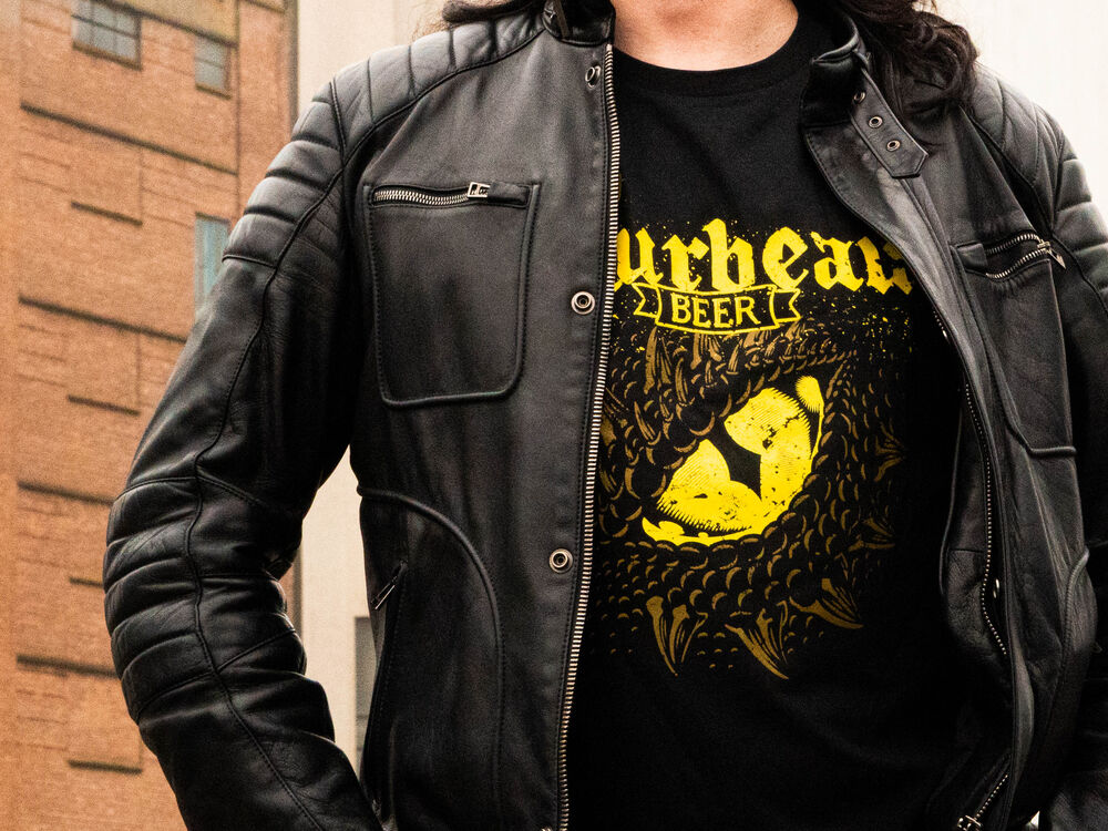 Ein Marken-T-Shirt, getragen unter einer Lederjacke, das Logo auf der Brust sichtbar