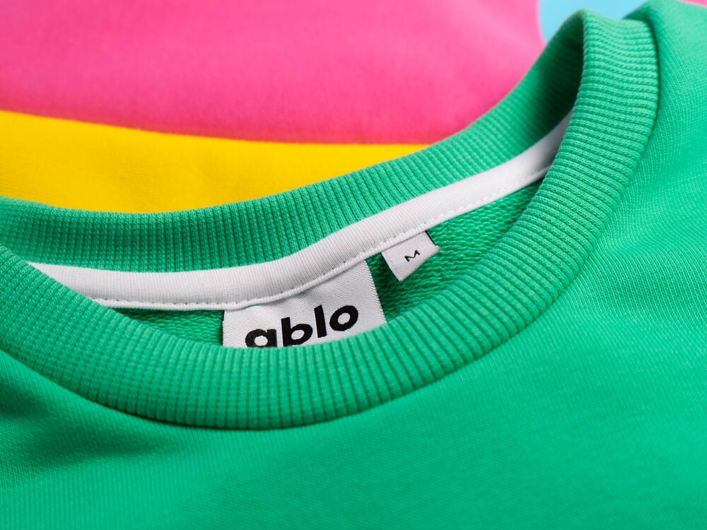Individuelle Firmenkleidung: Pullover in eigenen Hausfarben mit einem individuellen gewebten Nackenband