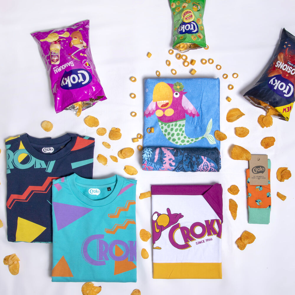 A branded collection laid out with folded t-shirts, a printed towel, socks and product packaging, showing the range a store rotates over a year