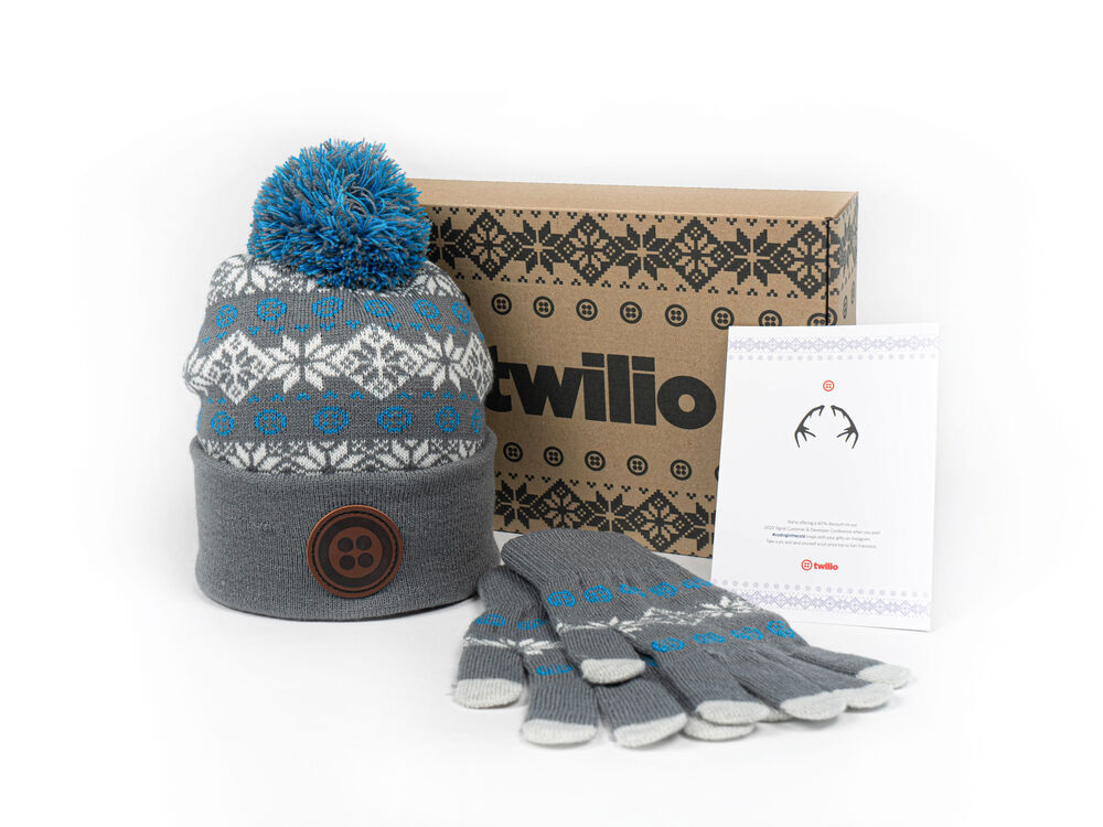 A branded winter gift kit with a beanie and gloves presented in a decorated box with a printed card, showing branding carried by the packaging
