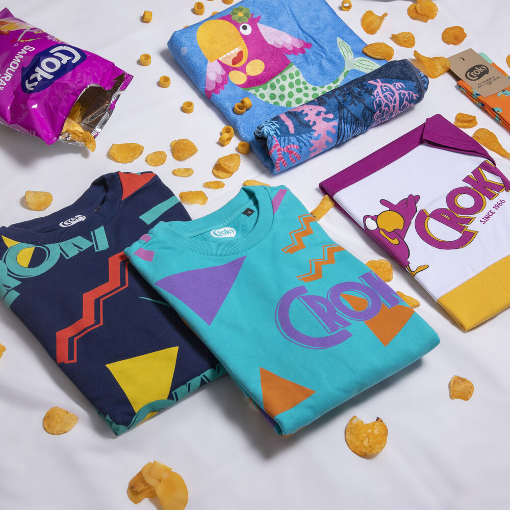 Camisetas de marca dobladas y una toalla estampada dispuestas con embalaje de producto, el tipo de envío que cruza una frontera con documentación aduanera