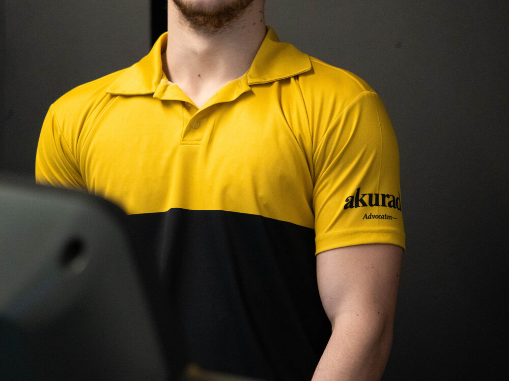Ärmeldetail eines Marken-Poloshirts mit einem aufgedruckten Partnerlogo am Arm