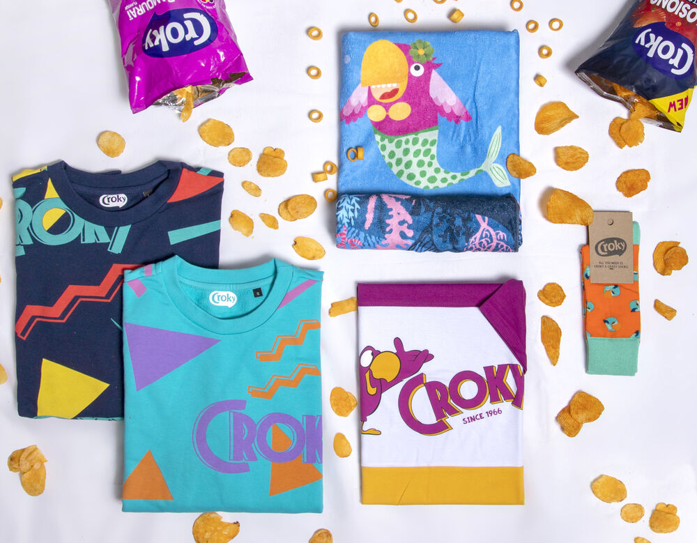 Une collection complète de goodies de marque disposée à plat avec t-shirts, serviette imprimée, chaussettes et emballage