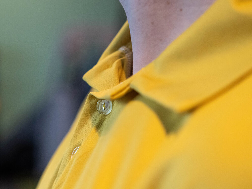 Close-up van de kraag en knopenlijst van een gepersonaliseerde bedrijfspolo in één merkkleur
