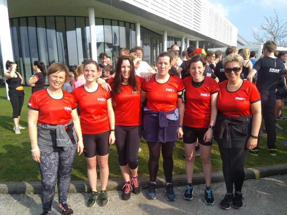 Eine Gruppe von Menschen in einheitlichen Marken-T-Shirts bei einem Firmenevent vor einem Bürogebäude