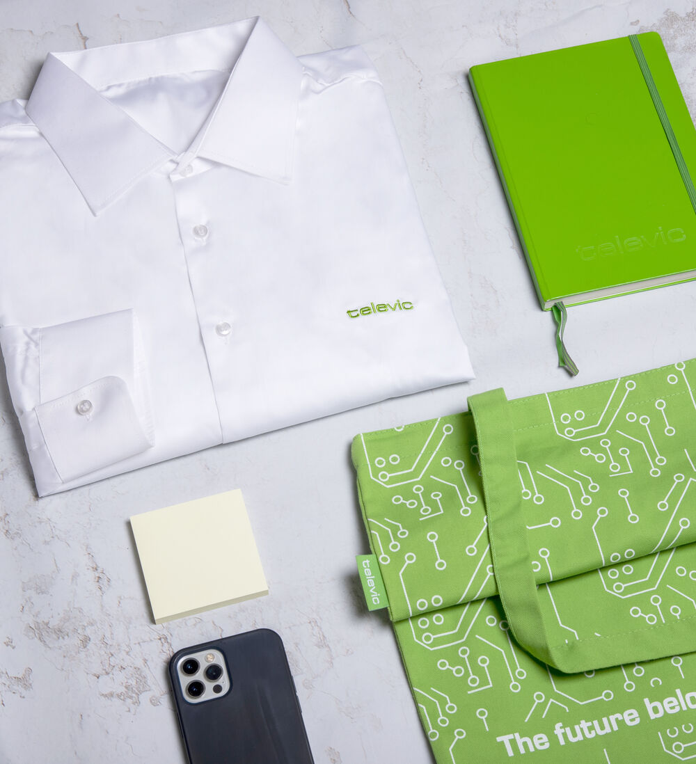 A branded shirt, notebook, tote bag and desk items laid out flat, showing the typical product mix used for corporate promotional gifts