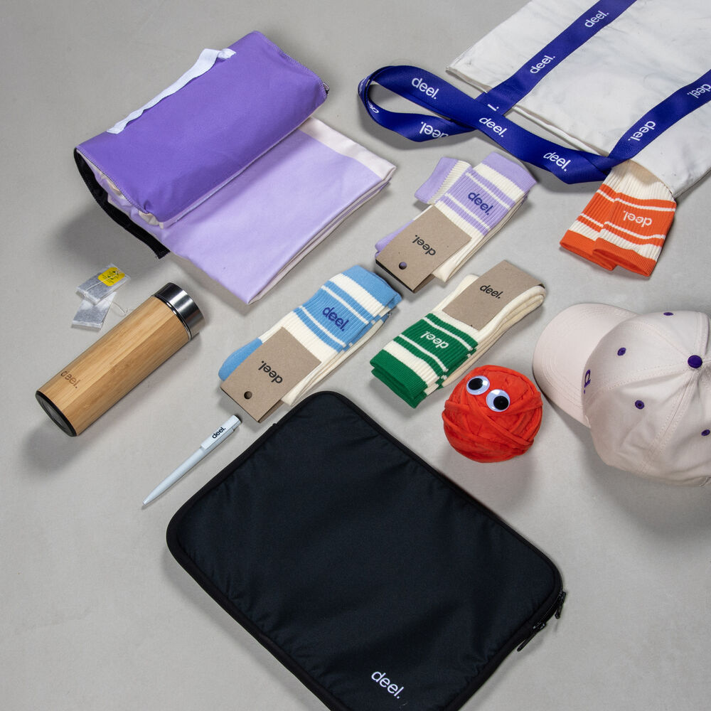 A flat-lay of a coordinated employee swag collection with a bottle, pouch, lanyards, cap and socks, showing how one internal collection covers many moments