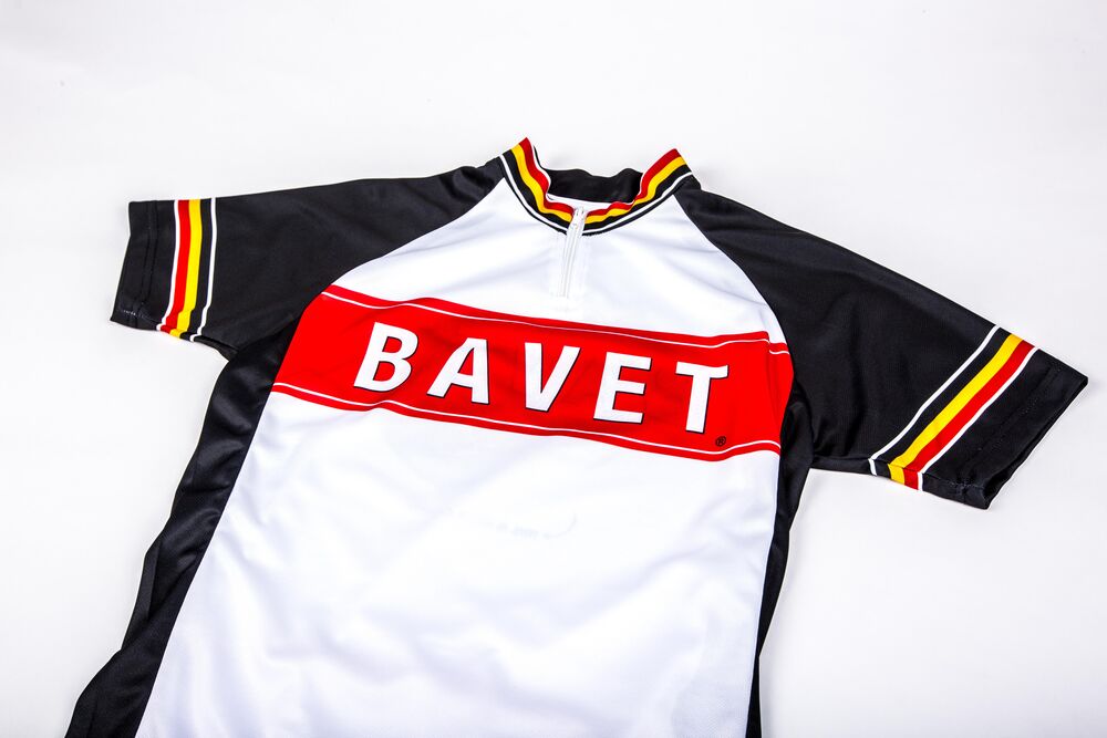 Un maillot de ciclismo negro, blanco y rojo con ribetes tricolores fotografiado sobre fondo blanco, un ejemplo de artículo de mayor valor donde tiene sentido una devolución estándar
