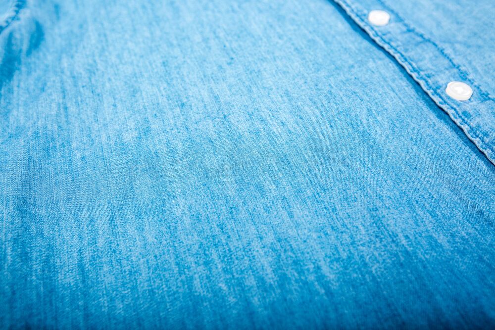Close-up van een blauw chambray overhemd met witte knopen, het soort kwalitatief eenmalig item dat een vooraf samengestelde swagbox verankert