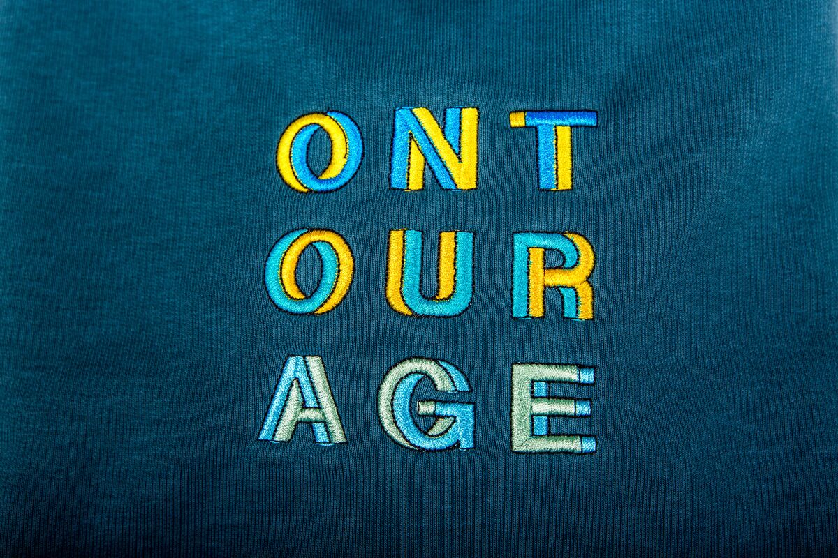 Close-up of multi-colour embroidered lettering on a teal sweatshirt, the kind of finishing that small-batch warehouse production makes possible