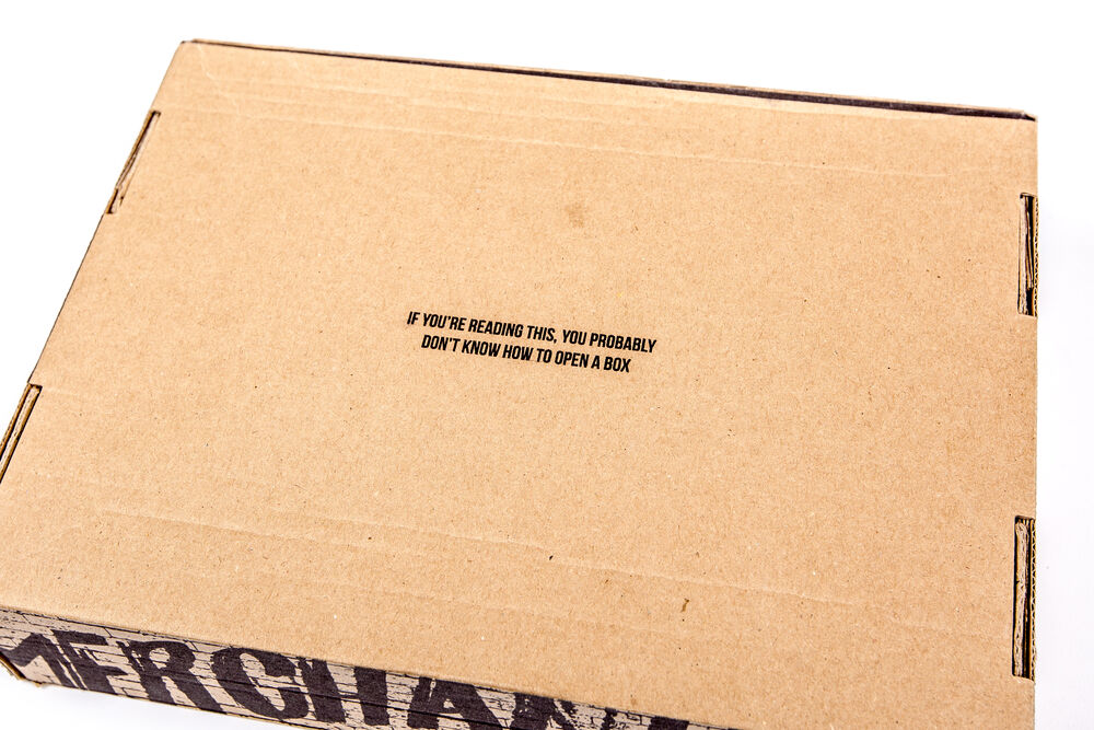 A plain kraft cardboard gift box with a small printed line of copy and no plastic, an example of low-waste packaging for eco friendly corporate gifts