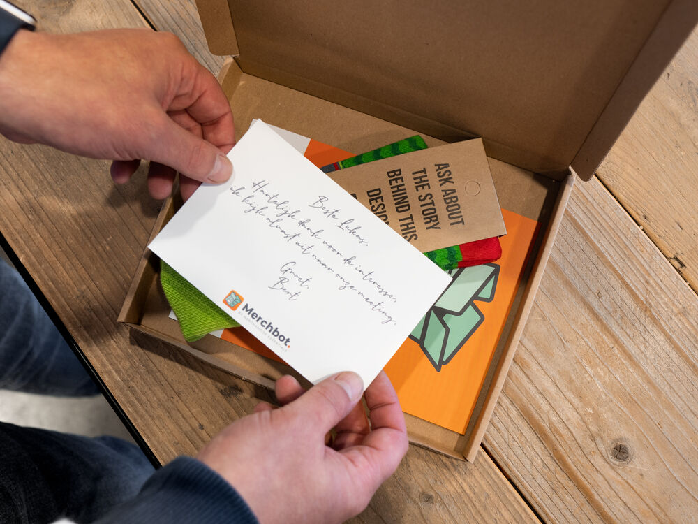 Eine geöffnete Kraftpapier-Geschenkbox mit individuellen Socken und einer handgeschriebenen Karte, das Auspackerlebnis, an dem ein guter Anbieter von Firmengeschenken gemessen wird