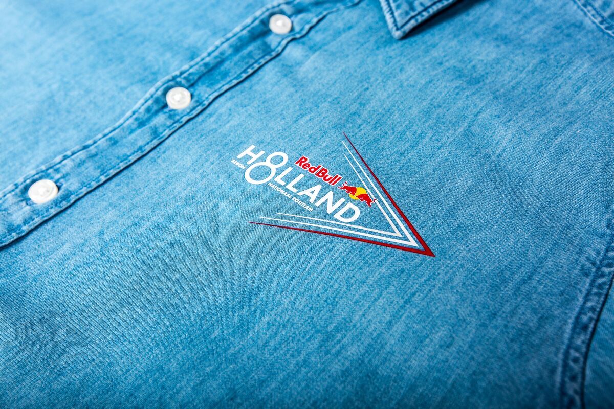 Nahaufnahme eines hellblauen Jeanshemds mit einem rot-weiß-blauen Logo auf der Brust