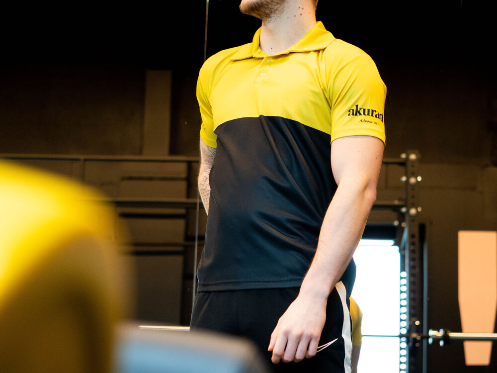 Ein Servicetechniker trägt ein zweifarbiges Corporate-Poloshirt in einer Werkstatt