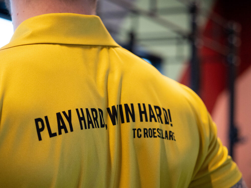 De achterkant van een gepersonaliseerde poloshirt bedrukt met de slogan van een lokale club naast het merkembleem