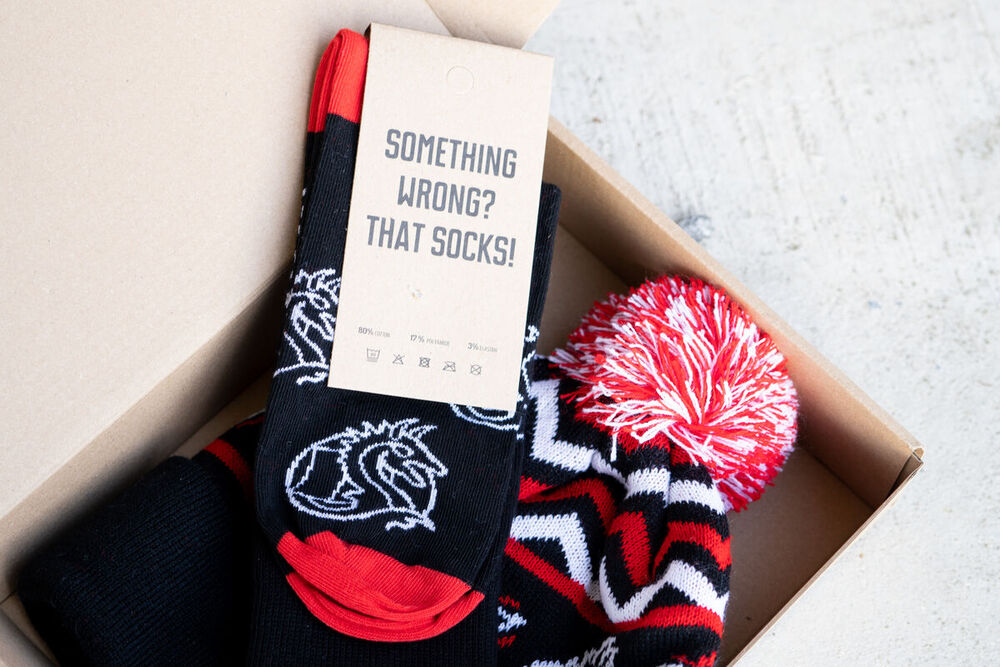 An open branded gift box containing socks, a knitted beanie and a printed message card, a gift built for one specific moment in a corporate gifting program