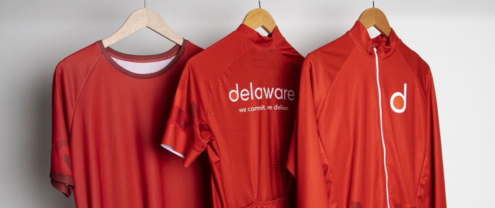 A branded apparel collection in a single brand colour hanging on a rail, the kind of internal range that suits employees rather than clients