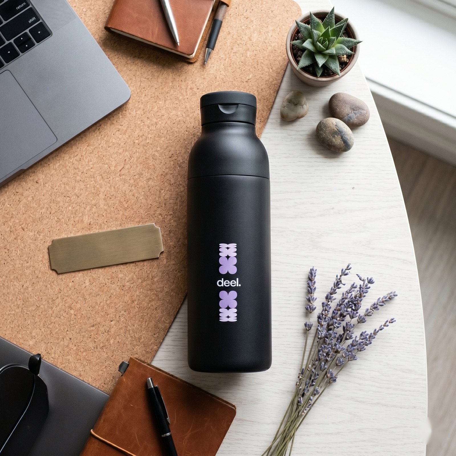 A black insulated stainless steel custom water bottle on a desk