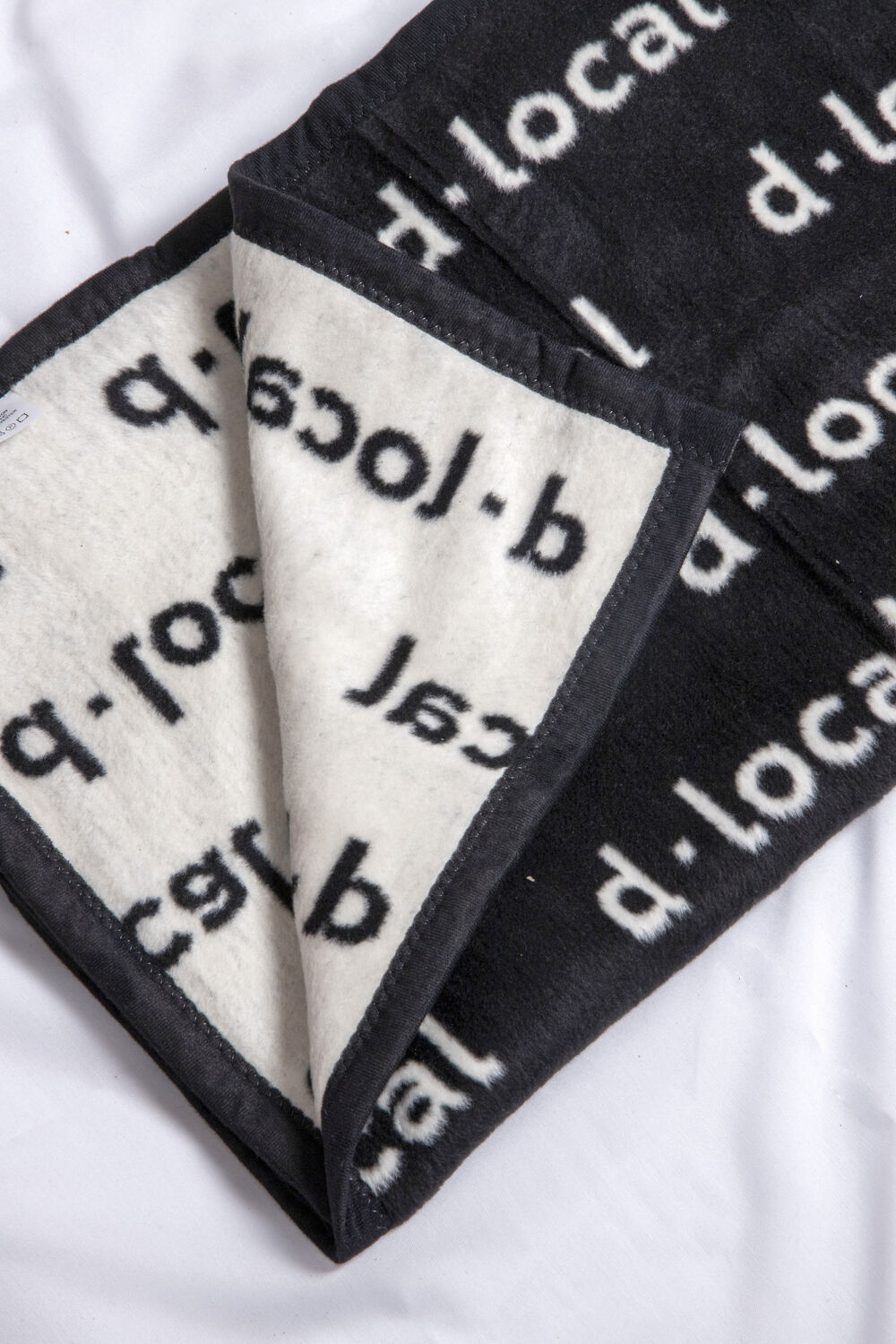 Custom branded deken voor dLocal van Sunday afgewerkt met een discreet label, de subtiele decoratieoptie